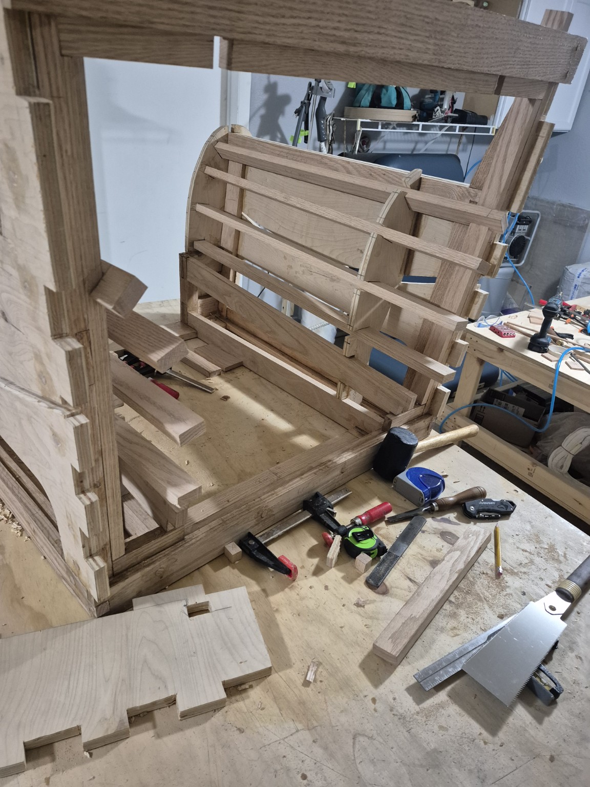 Chair frame during assembly with a handsaw and shaped wooden parts on the bench
