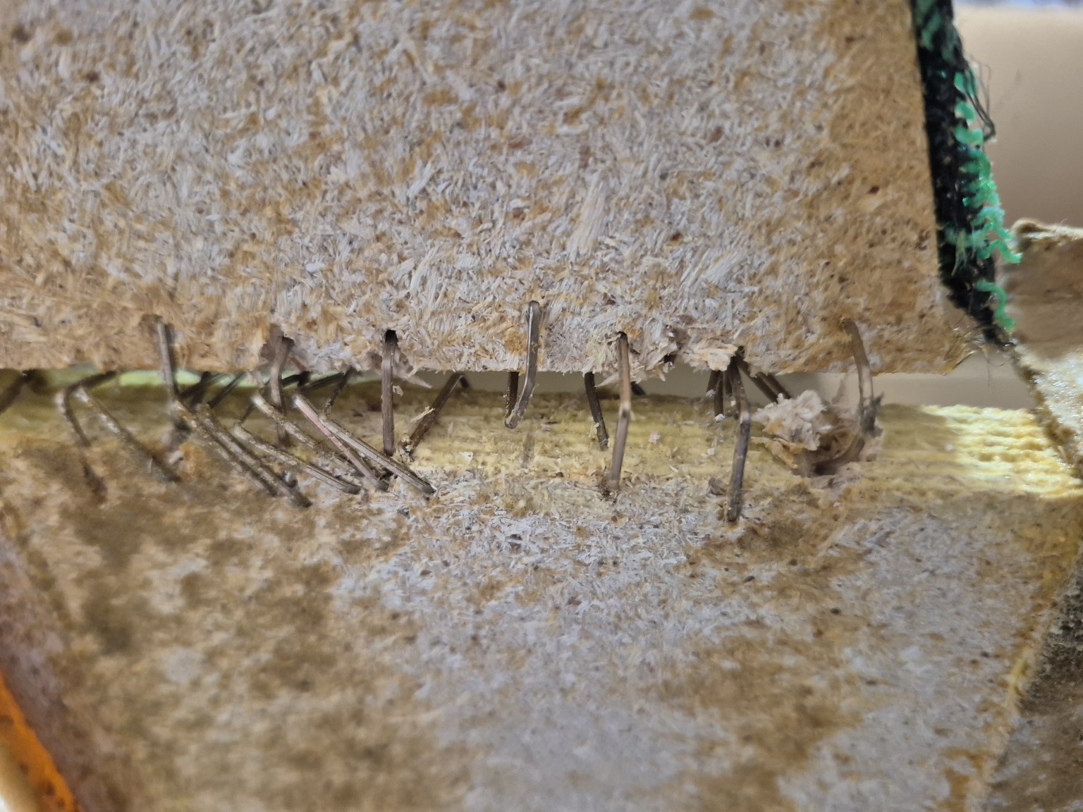 Exposed bent staples in a separated original particleboard connection